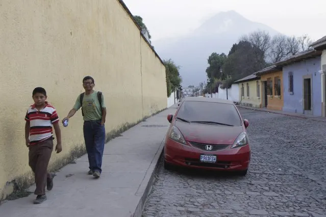 People walk near a car covered with ash in town of Antigua, on the outskirts of Guatemala City, February 7, 2015. Guatemala's Fuego volcano belched black ash into the sky on Saturday, causing the government to evacuate 100 nearby residents and forcing the closure of the capital's international airport, President Otto Perez told reporters. (Photo by Josue Decavele/Reuters)