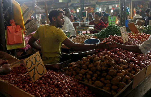 A vendor of a stall exchanges money with a customer at a main market in Colombo, Sri Lanka November 30, 2016. (Photo by Dinuka Liyanawatte/Reuters)