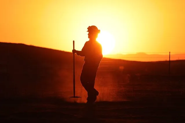 A CalFire crewman walks through the charred grass of the Almond Fire which burned over 5,200 acres (2100 hectares) in Lost Hills, California, August 6, 2023. (Photo by David Swanson/AFP Photo)