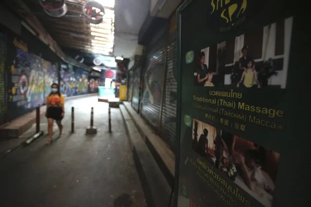 A passerby wearing a face mask to help curb the spread of the coronavirus moves past a closed massage shop in Khao San road, a popular hangout for Thais and tourists in Bangkok, Thailand, Monday, April 26, 2021. Cinemas, parks and gyms were among venues closed in Bangkok as Thailand sees its worst surge of the pandemic. A shortage of hospital beds, along with a failure to secure adequate coronavirus vaccine supplies, have pushed the government into imposing the new restrictions. (Photo by Anuthep Cheysakron/AP Photo)