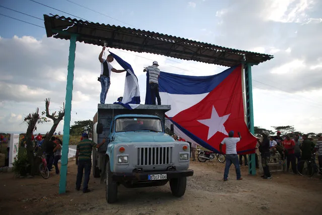 Men hang up the Cuban flag as they wait for the ashes of Cuba's former President Fidel Castro to pass during a journey to the eastern city of Santiago de Cuba, on the outskirts of Bayamo, Cuba, December 2, 2016. (Photo by Alexandre Meneghini/Reuters)