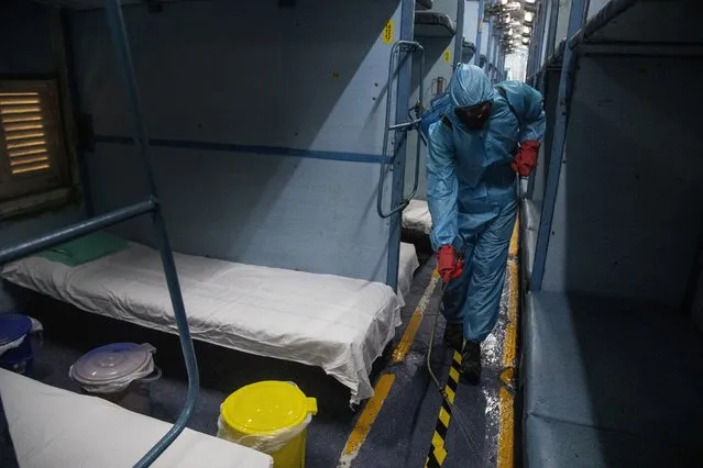 A health worker in personal protective equipment sanitizes a compartment of a train prepared as COVID-19 care centre in the wake of spike in the number of positive coronavirus cases, at a railway station in Gauhati, India, Thursday, May 6, 2021. (Photo by Anupam Nath/AP Photo)