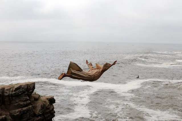 Fernando Jesus Canchari, dressed as a friar, jumps from a 13-meter high cliff along Herradura Beach in Lima, December 7, 2016. (Photo by Guadalupe Pardo/Reuters)