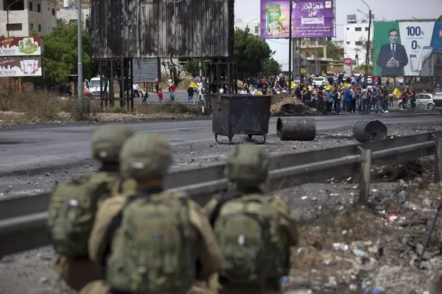 Palestinian demonstrators throws stones during clashes with Israeli security forces at the Hawara checkpoint, south of the West Bank city of Nablus Friday, May 21, 2021. (Photo by Majdi Mohammed/AP Photo)