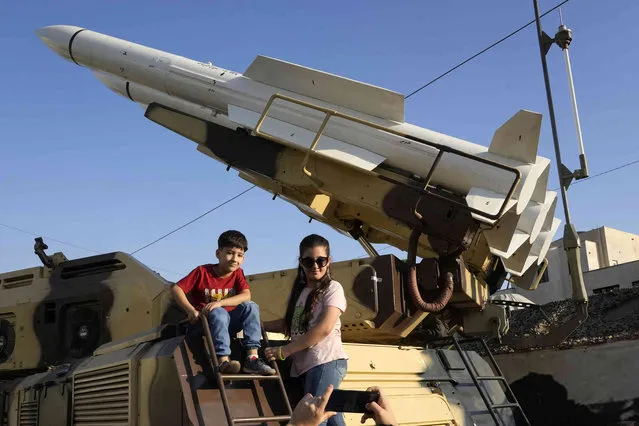 Children pose for a photo with a Third of Khordad air defense system in an exhibition by Iran's army and paramilitary Revolutionary Guard celebrating “Sacred Defense Week” commemorating the anniversary of the start of 1980-88 Iran-Iraq war, at Baharestan Sq. in downtown Tehran, Iran, Friday, September 29, 2023. (Photo by Vahid Salemi/AP Photo)