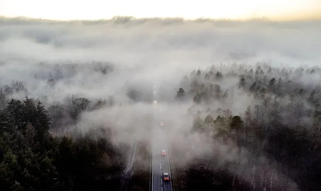 Vehicles move into the fog on a road in Wehrheim near Frankfurt, Germany, Tuesday evening, February 14, 2023. (Photo by Michael Probst/AP Photo)
