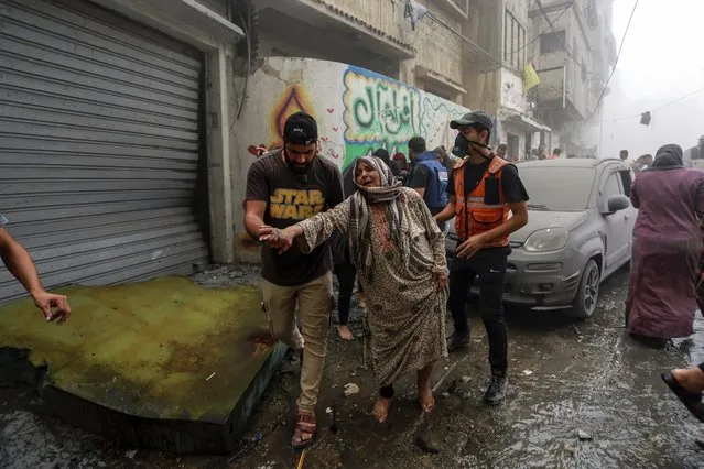 People help evacuate a Palestinian woman following Israeli airstrikes that targeted her neighbourhood in Gaza City, Monday, October 23, 2023. (Photo by Abed Khaled/AP Photo)