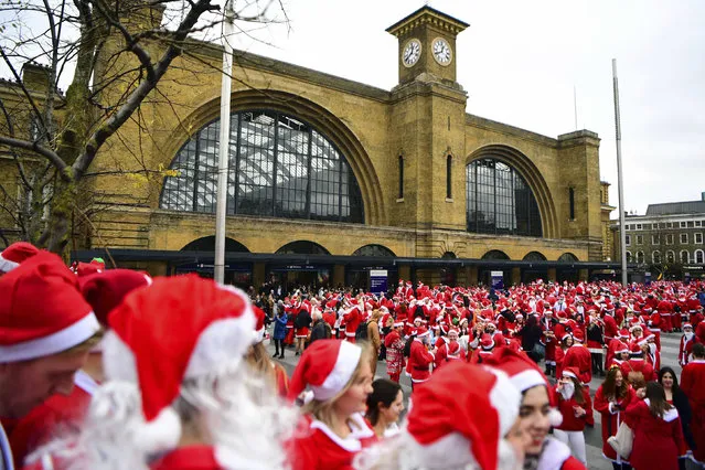 Participants in Santa costumes outside King's Cross station, as they make their way to take part in Santacon London 2018, in London, Saturday, December 8, 2018. (Photo by Gareth Fuller/PA Wire via AP Photo)