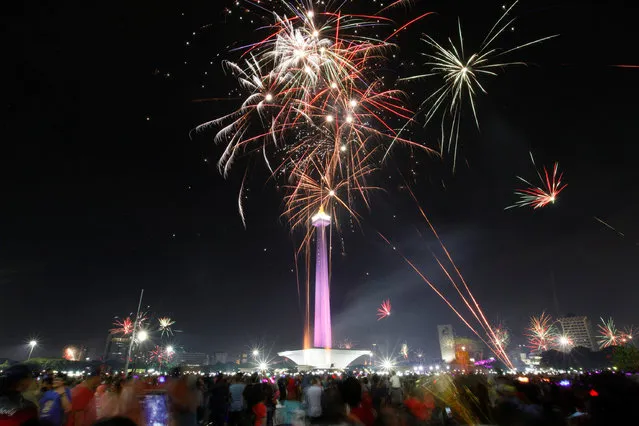 People watch fireworks explode around the National Monument during New Year's Eve celebrations in Jakarta, Indonesia January 1, 2017. (Photo by Fatima El-Kareem/Reuters)