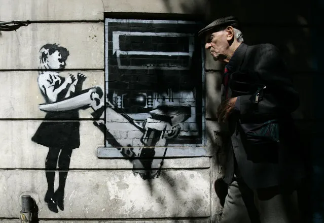 A man walks past a graffiti creation by Banksy at Exmouth Market in London in 2007. (Photo by Luke MacGregor/Reuters)