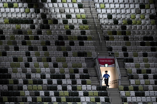 A police officer is seen in the empty stands ahead of the opening ceremony of the Tokyo 2020 Olympic Games, at the Olympic Stadium, in Tokyo, on July 23, 2021. (Photo by Martin Bureau/AFP Photo)