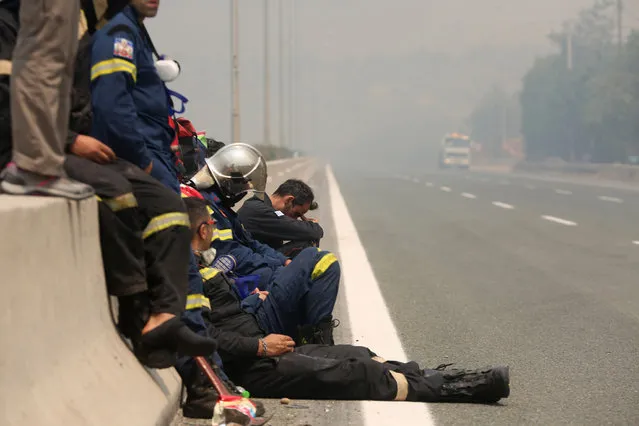 Firefighters are resting at the side of the Athens- Lamia national highway in Afidnes area, near Athens, Greece, 06 August 2021. The fires in Attica continued to blaze uncontrollably on Friday, along all three fronts that formed during the night – at the side of the Athens-Lamia national highway toward Kapandriti, on the foothills of Parnitha in Afidnes and in Ippokratios Politia where both homes and businesses were burned. Another major problem caused by the fires is the thick smoke that has blanketed the Attica sky, creating a stifling atmosphere. Among the forces fighting the flames are 83 fire-fighters sent from France, who arrived in Greece on 06 August. The situation, already extremely difficult, is expected to get worse during the day as wind intensity picks up and starts to fan the flames. (Photo by Alexander Beltes/EPA/EFE)
