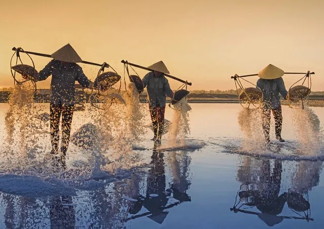 In the salt fields of Nha Trang, Vietnam, workers in October 2023 begin their day at 3am when the temperatures are bearable. Water flows through a network of canals to reach the fields, where it evaporates and the salt can be harvested. (Photo by Nguyen Minh Tuan/Solent News)