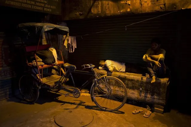 A man who lives in the street sleeps outside a closed shop as another sleeps in a cycle rickshaw in the morning in the old Delhi area of New Delhi, India, Tuesday, April 14, 2015. The four-century-old neighborhood is chaotic and crowded, yet is the vibrant heart of the city. (Photo by Bernat Armangue/AP Photo)