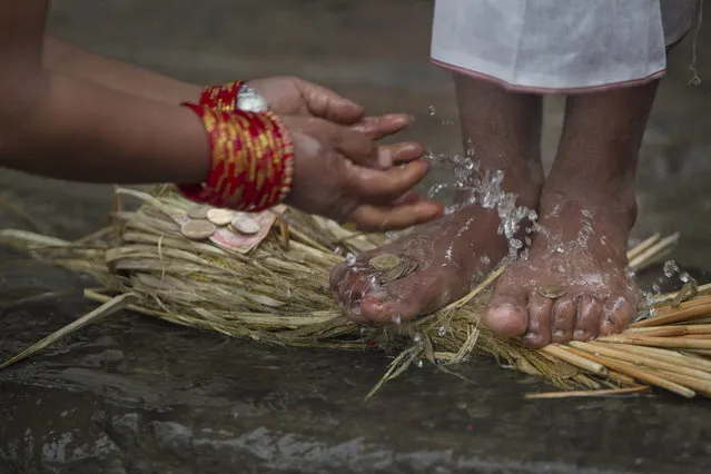 A Nepalese Hindu devotee sprinkles water and offer money on the feet of a priest as at the part of the ritual on the bank of the river Hanumante during the Madhav Narayan festival in Bhaktapur, Nepal, Thursday, January 24, 2019. During this festival, devotees recite holy scriptures dedicated to Hindu goddess Swasthani and Lord Shiva. Unmarried women pray to get a good husband while those married pray for the longevity of their husbands by observing a month-long fast. (Photo by Niranjan Shrestha/AP Photo)