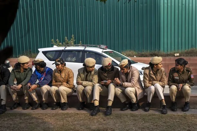 Delhi policewomen rest on a sidewalk ahead of a march by suspended lawmakers in New Delhi, India, Thursday, December 21, 2023. Dozens of opposition lawmakers suspended from Parliament by Prime Minister Narendra Modi's government for obstructing proceedings in the chamber held a street protest on Thursday accusing the government of throttling democracy in the country. (Photo by Altaf Qadri/AP Photo)