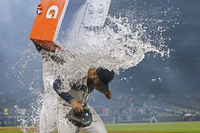 Seattle Mariners’ Abraham Toro, right, has a cooler of water dumped on him by teammate Luis Torrens, left, as Toro takes part in an interview after a baseball game against the Houston Astros, Tuesday, August 31, 2021, in Seattle. Toro hit a grand slam in the eighth inning to give the Mariners a 4-0 win. (Photo by Ted S. Warren/AP Photo)