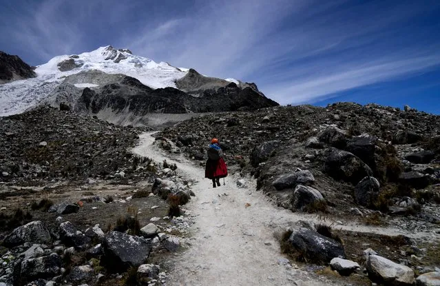 Cholita climber Suibel Gonzales walks towards the Huayna Potosi mountain snow-capped peak, near El Alto, Bolivia, Sunday, November 5, 2023. Dressed up on colorful, multilayered skirts, Gonzales is part of a group of 20 Indigenous Bolivian women who have been climbing the Andes peaks for the past eight years, working as guides for tourists. But as the glaciers in the South America country continue to retreat amid an increase in the average global temperature, they are worried about the future of their jobs. (Photo by Juan Karita/AP Photo)