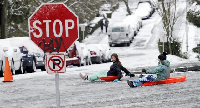 Children sled down one of Seattle's steeper hills, ice-covered Queen Anne Ave., Monday, February 4, 2019. Western Washington was hit by a major winter storm, with several inches of snow, cold temperatures and bone-chilling winds overnight and into the day Monday. (Photo by Elaine Thompson/AP Photo)
