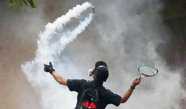 A demonstrator uses a racket against a tear gas canister during a protest for the government's handling of the coronavirus disease (COVID-19) pandemic, in Bangkok, Thailand on August 13, 2021. (Photo by Soe Zeya Tun/Reuters)