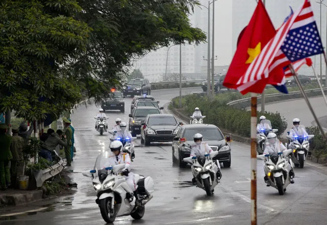 People wave Vietnam flags as a motorcade carrying North Korean leader Kim Jong Un is driven to Hanoi, Vietnam, Tuesday, February 26, 2019. (Photo by Gemunu Amarasinghe/AP Photo)