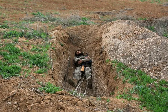 A rebel fighter sleeps with his weapon in a trench in Al-Lataminah village, northern Hama countryside, Syria March 5, 2016. (Photo by Ammar Abdullah/Reuters)
