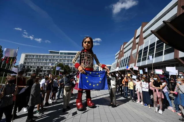 Members of the public gather as “Little Amal”, a giant puppet depicting a Syrian refugee girl, arrives with a European Union flag at the Council of Europe in Strasbourg, eastern France, on September 30, 2021, as part of the initiative “The Walk”. The initiative “The Walk”, that follows the journey of “Little Amal” travelling 8000km across Turkey and Europe, is aimed at creating awareness on the urgent needs of young refugees. (Photo by Frederick Florin/AFP Photo)