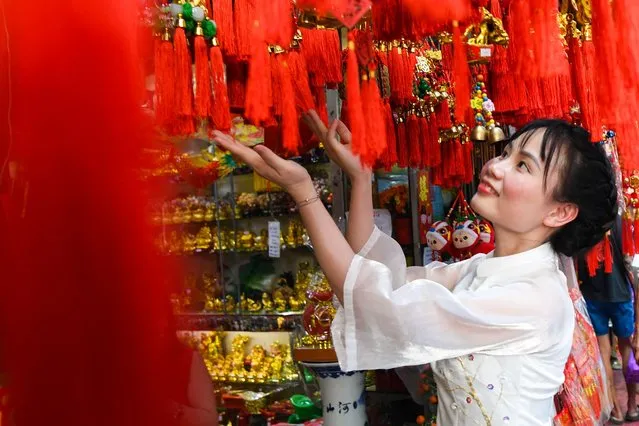A visitor poses next to Chinese charms and ornaments that are seen on display for sale at a shop in the Chinatown district of Manila on February 7, 2024, ahead of the Lunar New Year of the Dragon which falls on February 10. (Photo by Ted Aljibe/AFP Photo)