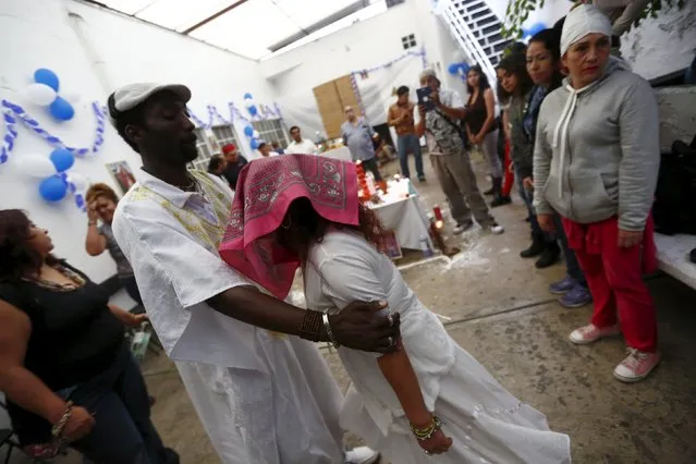 A woman faints while held by a voodoo priest as part of a trance during a voodoo ceremony in honor of Kouzen Zaka, also known as St. Isidro, in Mexico City, May 2, 2015. According to Haitain voodoo, Kouzen Zaka is the patron of work, whose patronage will help with employment and safeguard crops from robbers. (Photo by Edgard Garrido/Reuters)