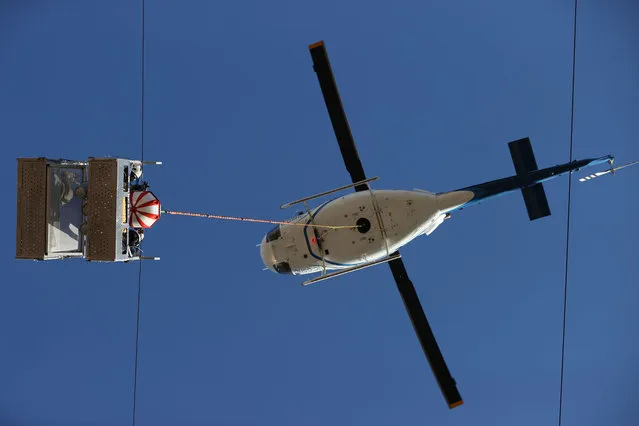 Maintenance team of Turkish Electricity Transmission Corporation (TEIAS) conducts an installation work of marker balls on 170 thousand volt transmission line from a basket lowered by a rope attached to the helicopter near Yunuseli Airport in Osmangazi district of Bursa, Turkey on September 30, 2021. (Photo by Ali Atmaca/Anadolu Agency via Getty Images)