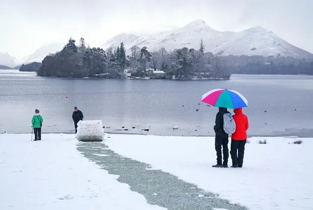 People walking in snowy conditions in Crow Park at Derwent Water in Keswick, Cumbria, UK on Tuesday, January 16, 2024. Much of Britain is facing another day of cold temperatures and travel disruption after overnight lows dropped below freezing for the bulk of the country. A “cold plunge of Arctic air” has moved south across the whole country over the past few days, making it 5C-6C lower than usual for this time of year, the Met Office said. (Photo by Owen Humphreys/PA Images via Getty Images)