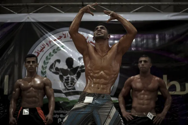 In this Friday, October 26, 2018 photo, Palestinian contestants, including Abdallah al-Hour, 20, center, perform on stage during a local bodybuilding competition, in Gaza City. In the end, al-Hour, 20, was crowned the winner in his weight category, in front of his home crowd and hoisted on the shoulders of his supporters in the packed, all-male gymnasium. (Photo by Khalil Hamra/AP Photo)