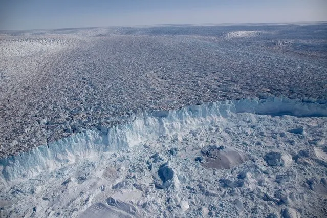 The Sermeq Kujalleq glacier, entering the Kangia Ilulissat Icefjord full of icebergs, August 2019. Sermeq Kujalleq is one of the world’s most productive glaciers and the fastest moving one in the world. Within the past 10 years, the glacier has doubled its speed and today it moves about 40 metres every 24 hours. This is because ice from a very large drainage area is concentrated in a narrow stream that follows a deep trough under the glacier. Scientists also believe that rising temperatures result in increasing amounts of meltwater under the glacier. (Photo by Michel Roggo/naturepl.com/LDY Agency)