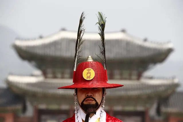 A South Korean official wearing a Royal Guard uniform stands guard before the Royal Palace gates during the Royal Guard changing ceremony at Gyeongbokgung Palace in Seoul, South Korea, 30 March 2016. In ancient times, the royal guards of Joseon Dynasty performed the given task by guarding the Gwanghwamun gate, the entrance of Gyeongbokgung Palace, where the king ruled the country. Since 1469, the ceremony has taken place and its record has been consulted for the present reenactment ceremony. (Photo by Jeon Heon-Kyun/EPA)