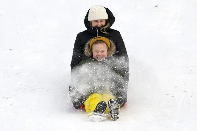 Tylor Perillo, 5, kicks up snows as she and her aunt Loraie Tylor sled down a city park hill where nearly a foot of snow fell over the weekend, Monday, December 27, 2021, in Bellingham, Wash. Emergency warming shelters were opened throughout western Washington and Oregon as temperatures plunged into the teens and forecasters said an arctic blast would last for several days. (Photo by Elaine Thompson/AP Photo)
