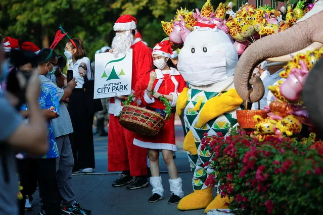 A girl poses in a Santa Claus costume during the visit of five elephants in Santa Claus costumes with giant face masks, delivering hand sanitizers and promoting a “get vaccinated” message at a primary school, in the historical city of Ayutthaya, Thailand, December  24, 2021. (Photo by Soe Zeya Tun/Reuters)