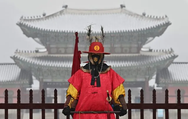A “palace guard” stands for tourists in front of the snow-covered Gyeongbokgung Palace in central Seoul on January 19, 2022. (Photo by Jung Yeon-je/AFP Photo)