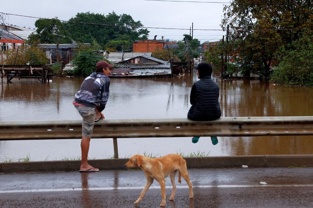 Men chat as they monitor their houses from a distance for fear of theft during floods in Porto Alegre, Rio Grande do Sul state, Brazil on May 12, 2024. (Photo by Amanda Perobelli/Reuters)