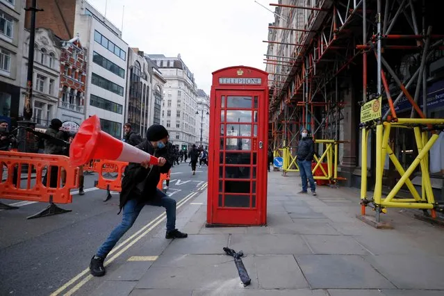 A demonstrator hits a telephone box with a road cone during a “Kill The Bill” protest against the Government's Police, Crime, Sentencing and Courts Bill in central London on April 3, 2021. The police, crime, sentencing and courts bill would give police in England and Wales more power to impose conditions on peaceful protests, including those they deem to be too noisy or a nuisance to the community. Critics argue this infringes on the right to free and peaceful expression. (Photo by Tolga Akmen/AFP Photo)