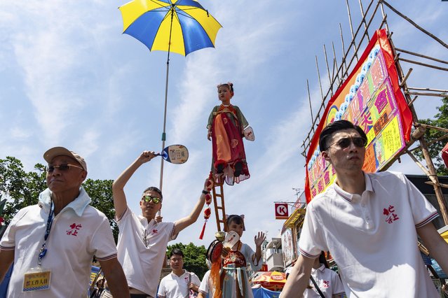 A child is hoisted up as participants take part in the Piu Sik Parade at the Bun Festival in Cheung Chau Island in Hong Kong, Wednesday, May 15, 2024. (Photo by Chan Long Hei/AP Photo)