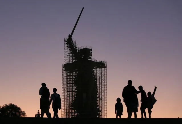 People walk near the statue “The Motherland Calls” under reconstruction in Mamayev Kurgan, the main place of the Battle of Stalingrad memorial, during sunset in Volgograd, Russia, Monday, August 12, 2019. (Photo by Dmitriy Rogulin/AP Photo)