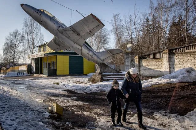 A woman walks underneath a military plane set as a monument to a former military base at a town on the outskirts of the Three Sisters border crossing between, Ukraine, Russia and Belarus on February 14, 2022 in Senkivka, Ukraine. Russian forces are conducting large-scale military exercises in Belarus, across Ukraine's northern border, amid a tense diplomatic standoff between Russia and Ukraine's Western allies. Ukraine has warned that it is virtually encircled, with Russian troops massed on its northern, eastern and southern borders. The United States and other NATO countries have issued urgent alerts about a potential Russian invasion, hoping to deter Vladimir Putin by exposing his plans, while trying to negotiate a diplomatic solution. (Photo by Chris McGrath/Getty Images)