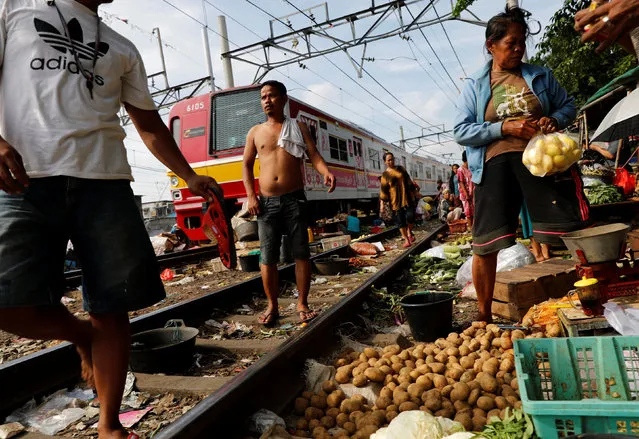 A vendor (R) serves a customer at a vegetable market as a commuter train passes by in Jakarta, Indonesia, May 4, 2016. (Photo by Reuters/Beawiharta)
