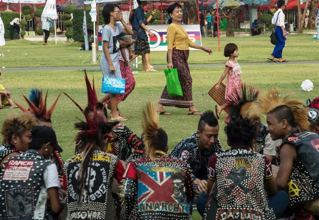 Women and a child walk past a punk group gathered in a park in central Yangon on April 12, 2017 on the eve of the water festival known as Thingyan. (Photo by Roberto Schmidt/AFP Photo)