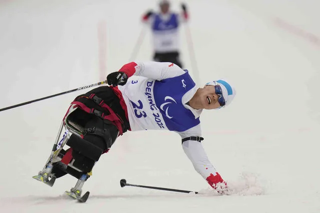 Zhu Yunfeng of China loses balance during the men's individual sitting event of para biathlon at the 2022 Winter Paralympics, Friday, March 11, 2022, in Zhangjiakou, China. (Photo by Shuji Kajiyama/AP Photo)
