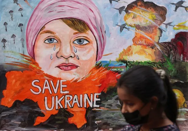 A girl walks past a painting depicting the crisis between Russia and Ukraine, outside an art school in Mumbai, India, February 24, 2022. (Photo by Francis Mascarenhas/Reuters)