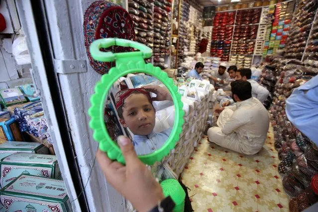 A Pakistani tries on a new prayer cap, ahead of the holy month of Ramadan in Peshawar, Pakistan, 29 March 2022. Muslims around the world celebrate the holy month of Ramadan, by praying during the night time and abstaining from eating, drinking, and sexual acts during the period between sunrise and sunset. Ramadan is the ninth month in the Islamic calendar and it is believed that the revelation of the first verse in Koran was during its last 10 nights. (Photo by Arshad Arbab/EPA/EFE)