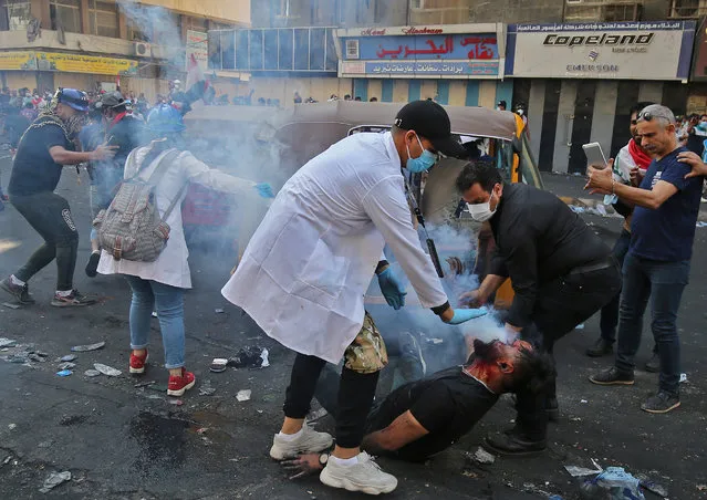 Iraqi volunteers help a protester who was struck by a tear gas canister fired by Iraqi security forces at Baghdad's Khallani square during ongoing anti-government demonstrations on November 11, 2019. The United States has urged Iraq to hold early polls and carry out electoral reform, after a rights group warned a deadly crackdown on anti-government protesters could spiral into a “bloodbath”. Three protesters were shot dead in the southern city of Nasiriyah on November 10 while dozens of demonstrators were wounded in Baghdad. (Photo by Ahmad Al-Rubaye/AFP Photo)
