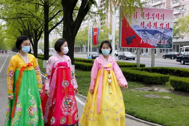 Women dressed in traditional Korean attire walk past a celebrative poster on the 90th founding anniversary of the Korean People's Revolutionary Army in Pyongyang, North Korea, Monday, April 25, 2022. The poster reads “Historic root of our revolution”. (Photo by Jon Chol Jin/AP Photo)