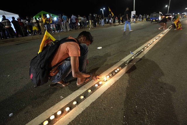 Sri Lankans light candles during a vigil condemning police shooting at protesters in Rambukkana, 90 kilometers (55 miles) northeast of Colombo, at a protest outside the president's office in Colombo, Sri Lanka, Tuesday, April 19, 2022. Sri Lankan police opened fire Tuesday at a group of people protesting new fuel price increases, killing one and injuring 10 others, in the first shooting by security forces during weeks of demonstrations over the country's worst economic crisis in decades. (Photo by Eranga Jayawardena/AP Photo)
